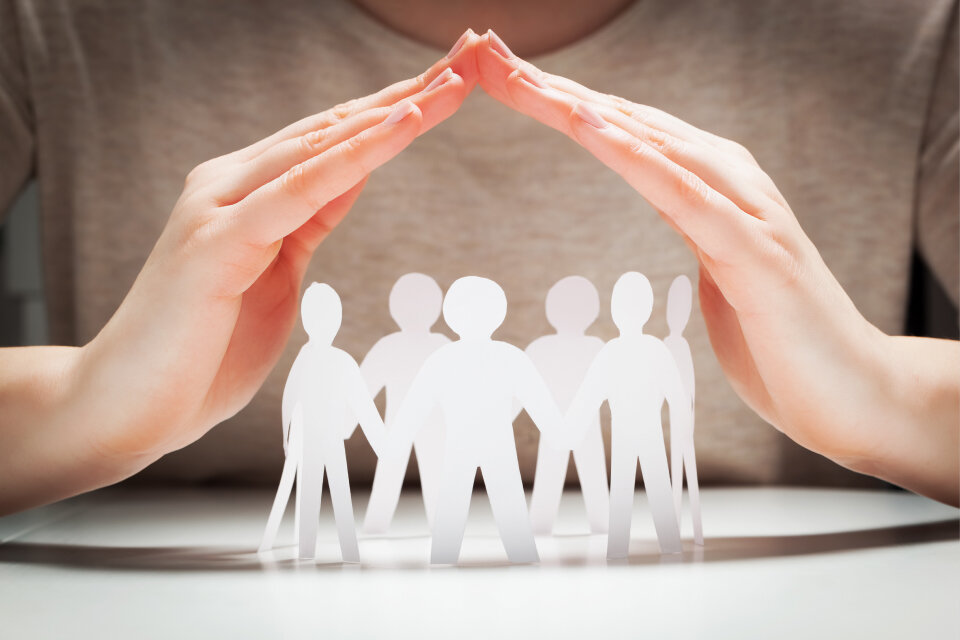 Zwei schützende Hände bilden ein Dach über einer Gruppe aus Papierfiguren – das Bild symbolisiert den Schutz der Betriebsräte. Zwei schützende Hände bilden ein Dach über einer Gruppe aus Papierfiguren – das Bild symbolisiert den Schutz der Betriebsräte.